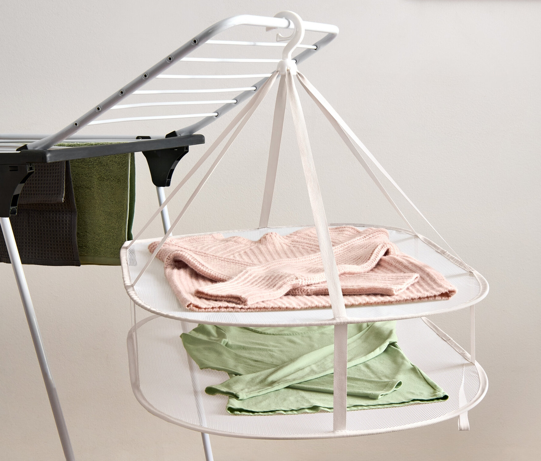 Na sušáku visí růžový svetr a zelené tričko.