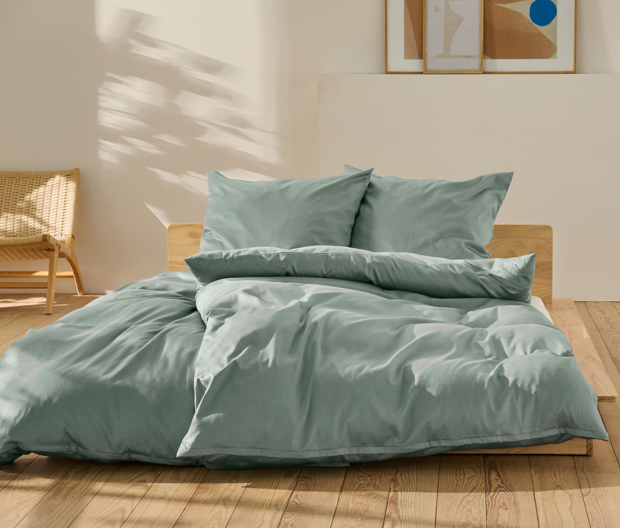 Zelené bavlněné saténové povlečení standardní a nadměrné velikosti na posteli.