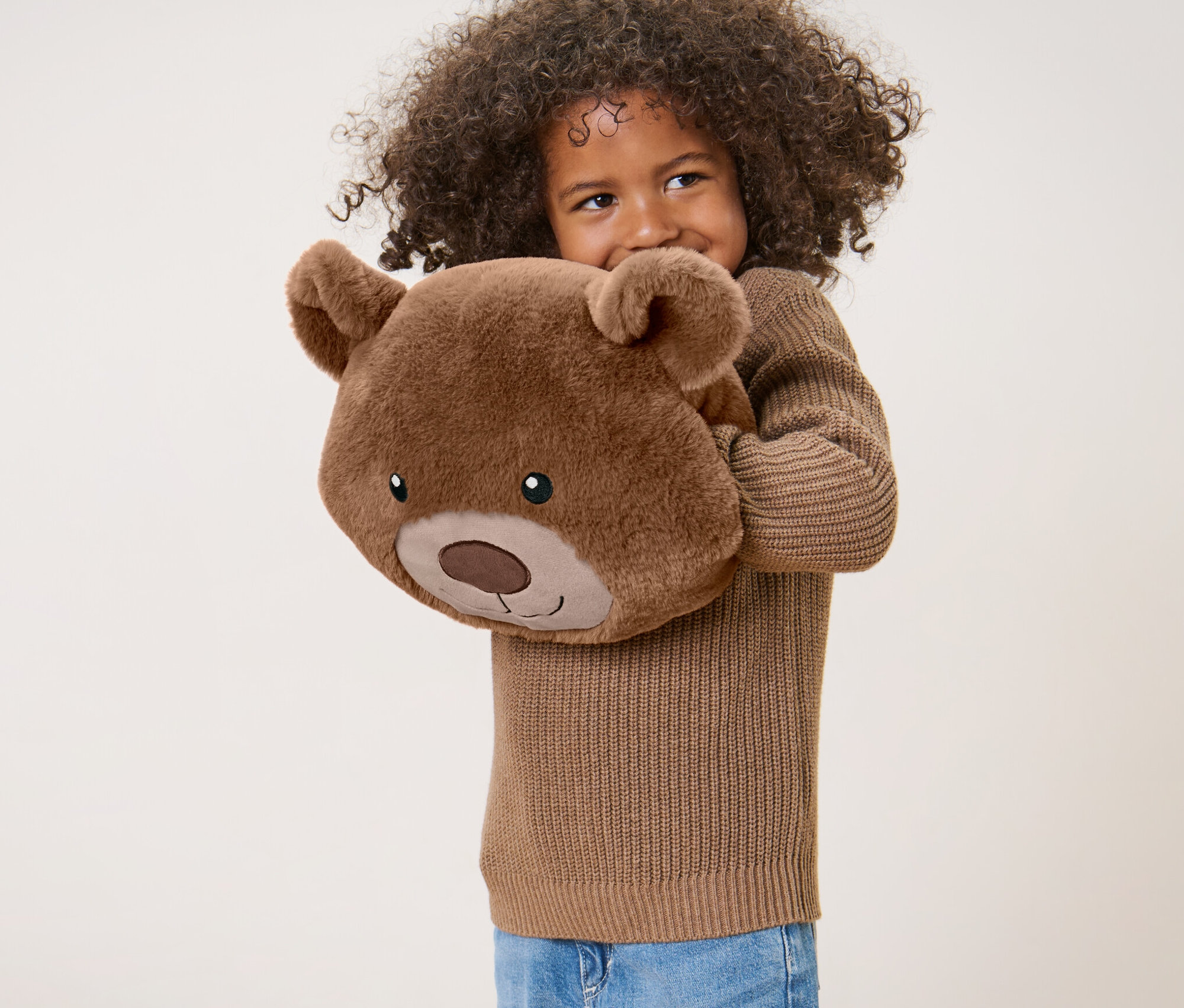 Dívka s kudrnatými vlasy drží plyšový polštářek »Medvídek«.