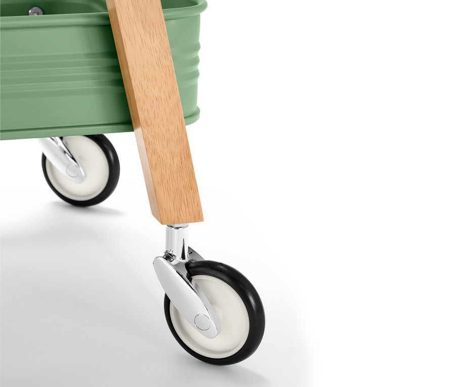 Detail kuchyňského servírovacího vozíku se zelenou horní částí, dřevěnou rukojetí a koly.