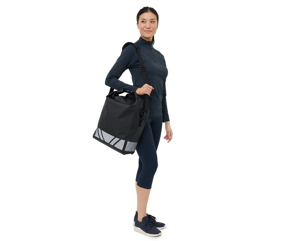 Žena nese přes rameno černou nepromokavou tašku na kolo.