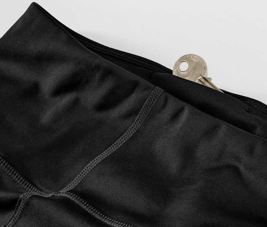 Detail černých sportovních legín s klíčem v kapse.