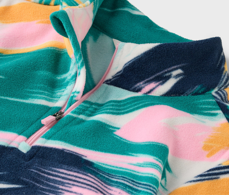 Detailní záběr na vzorovanou fleecovou mikinu s krátkým zipem.