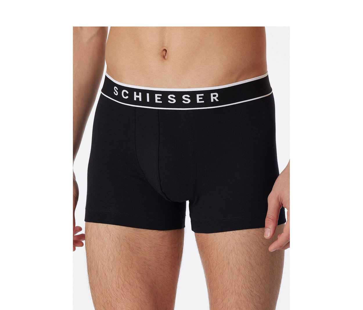 Muž v černých boxerkách SCHIESSER s bílým pasem s logem značky.