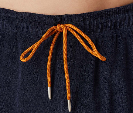 Detail modrých šortek s oranžovou stahovací šňůrkou.