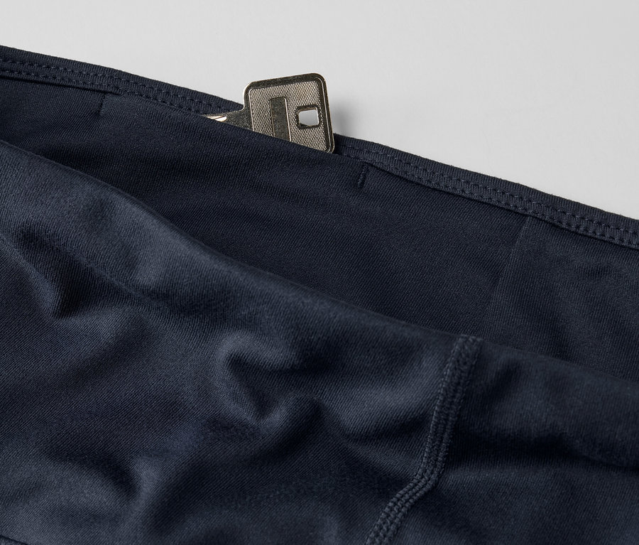 Detail tmavě modrých sportovních cyklistických šortek s klíčem v kapse.