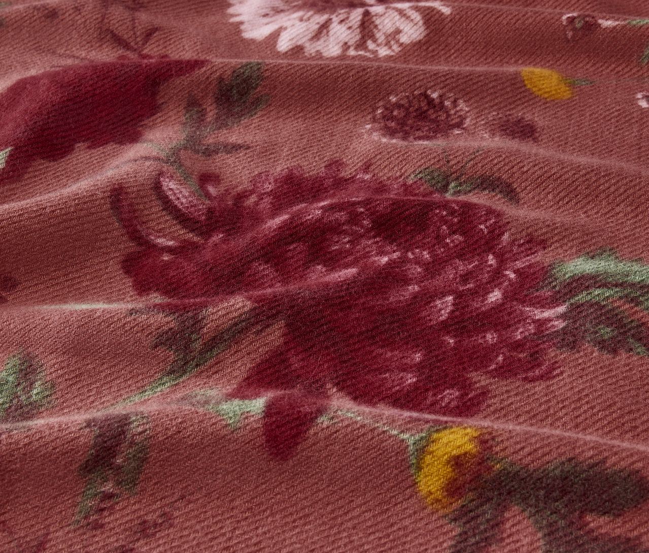 Detailní záběr na látku s květinovým vzorem v odstínech růžové a zelené.