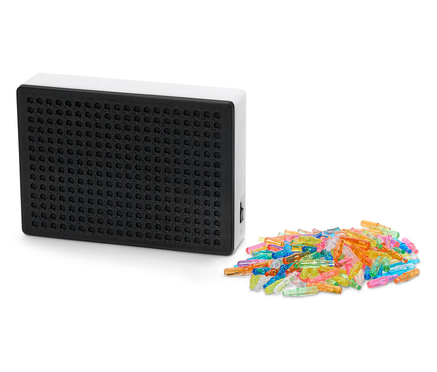 Černá světelná tabule s bílým rámem vedle hromady barevných kolíčků.