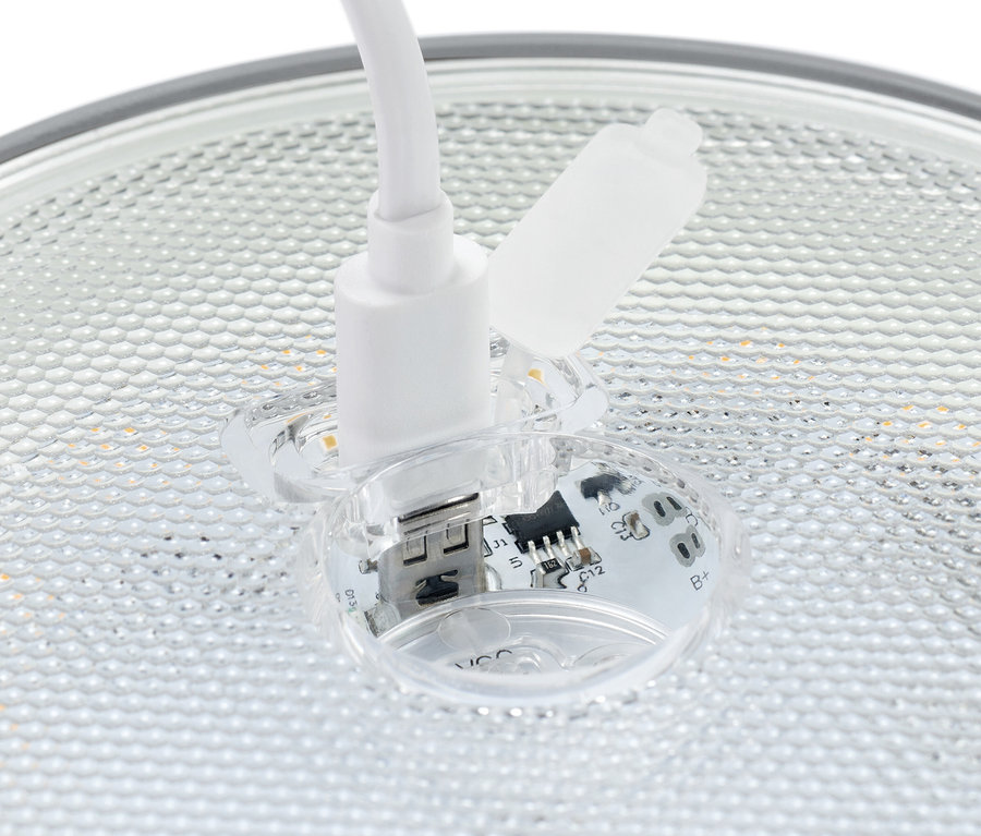 Detailní záběr bílého USB konektoru zasunutého do průhledné zásuvky s viditelnými elektronickými součástkami.