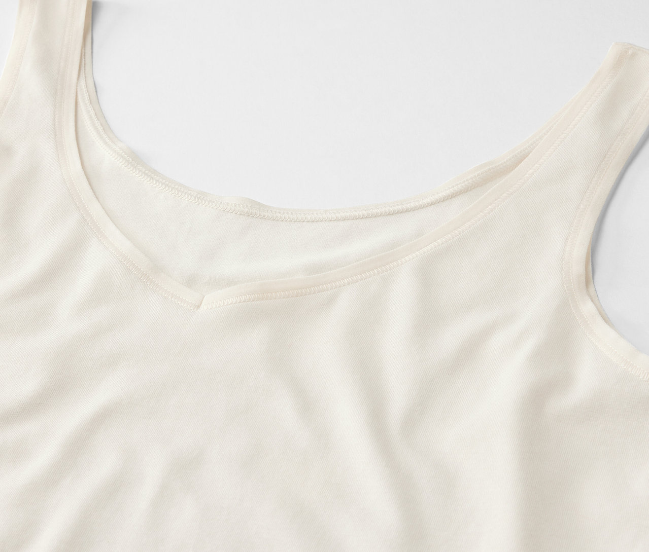 Detail krémového tílka s výstřihem do V.