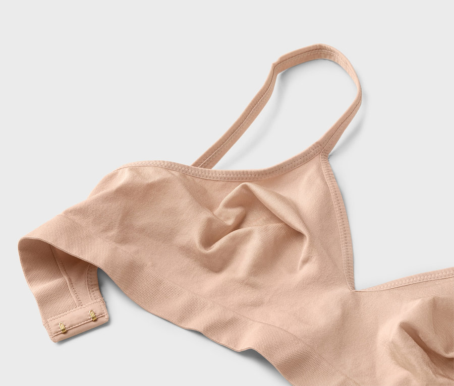 Detailní záběr tělové podprsenky s tenkými ramínky a zlatými háčky.