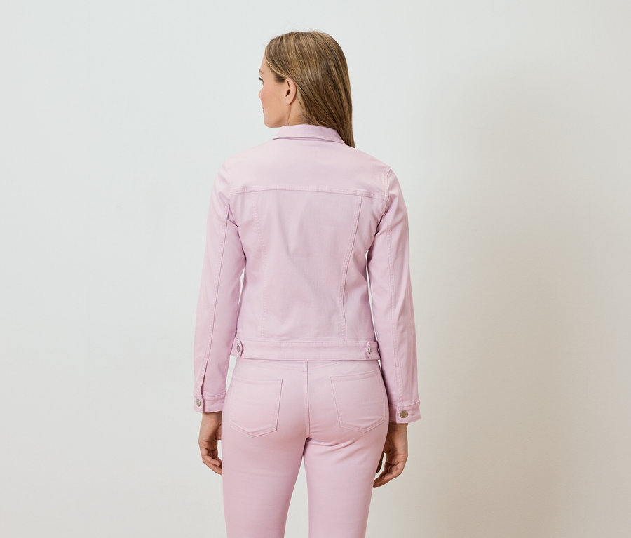 Žena zezadu, oblečená v růžové džínové bundě a odpovídajících kalhotách.