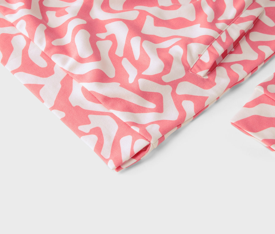 Detail oděvu s abstraktním růžovo-bílým vzorem.