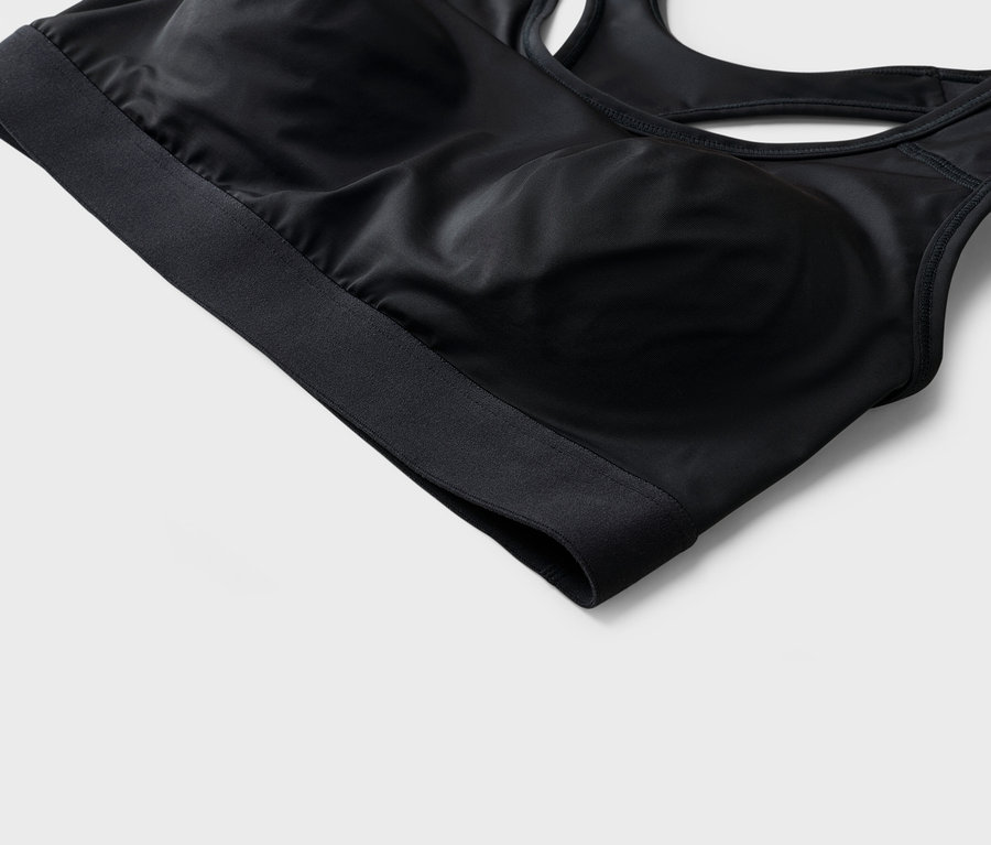 Detailní záběr na černou sportovní podprsenku se širokým spodním pásem.