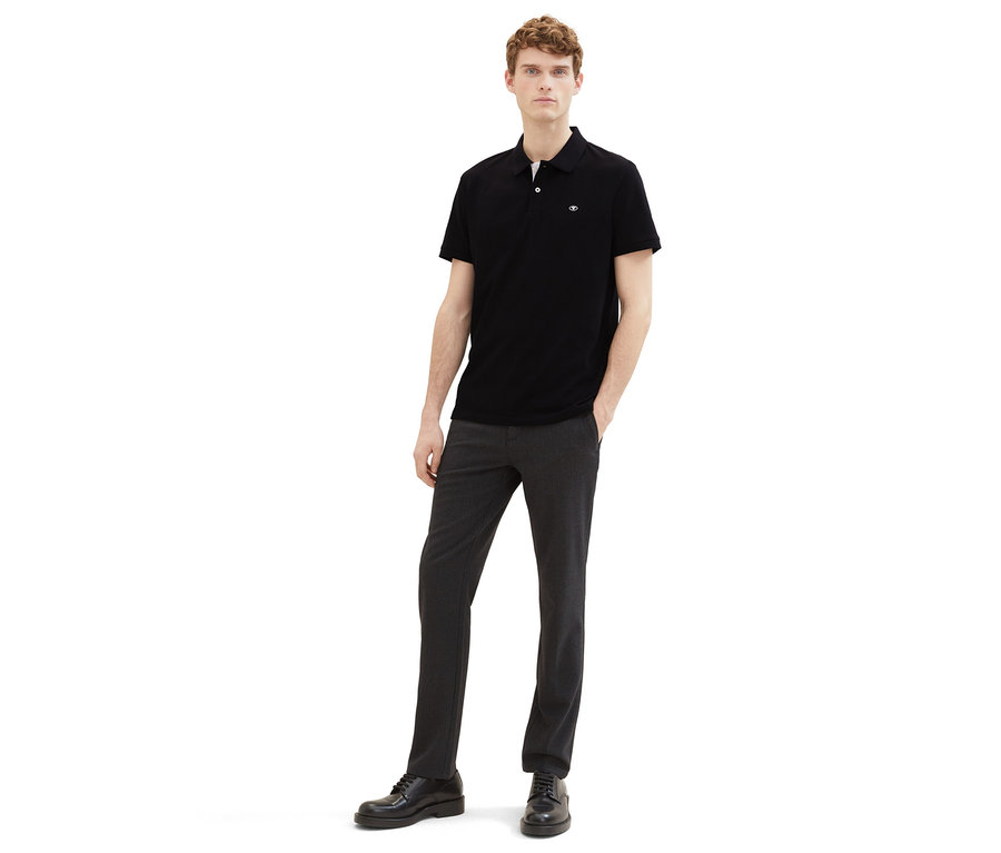 Muž v tmavých kalhotách a černá polokošile z piké Tom Tailor.