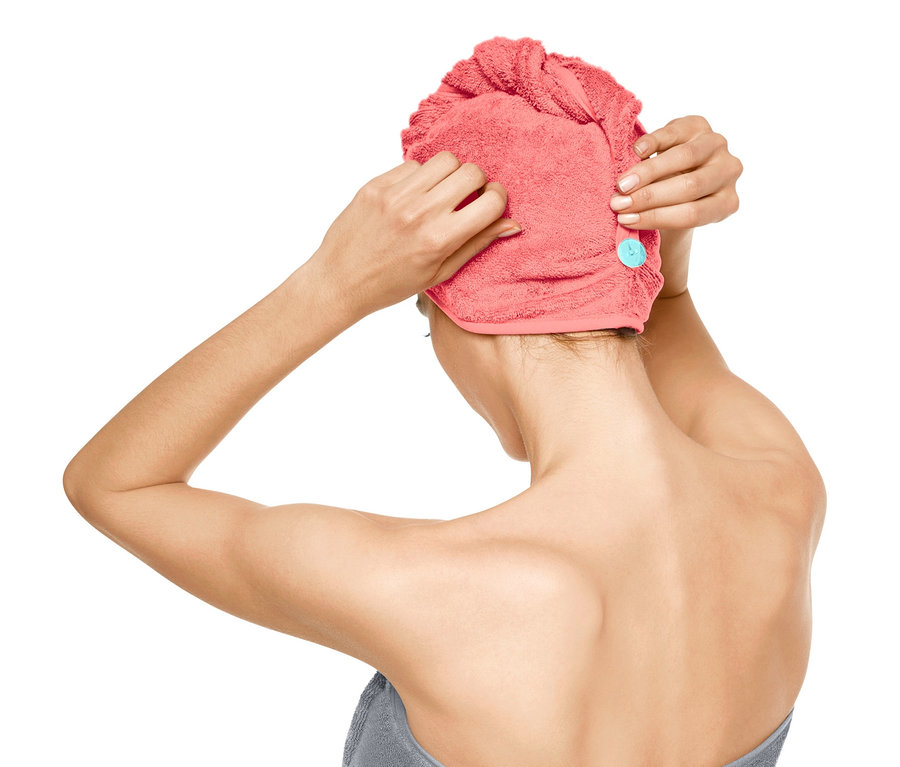 Žena si nasazuje ručníkový turban.