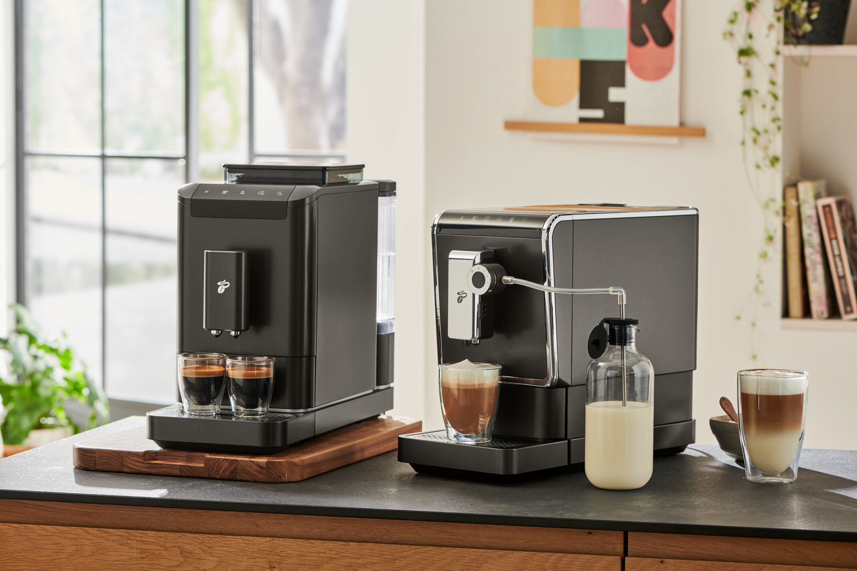 Dva kávovary stojí vedle sebe. U jednoho je karafa na mléko Esperto Pro a Esperto2 Milk a dva šálky.