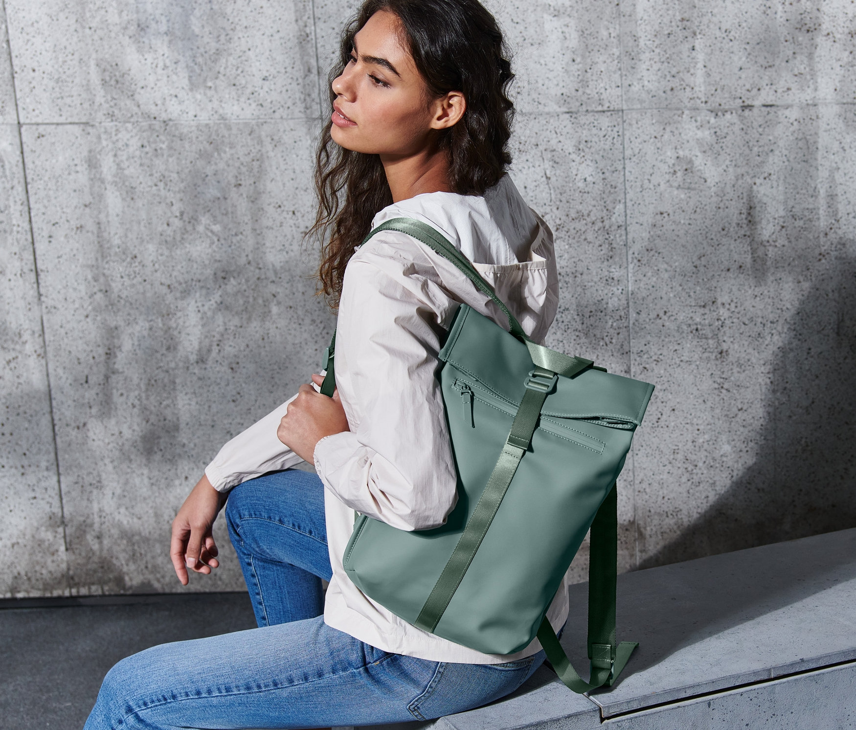 Žena sedí s batohem do deště.