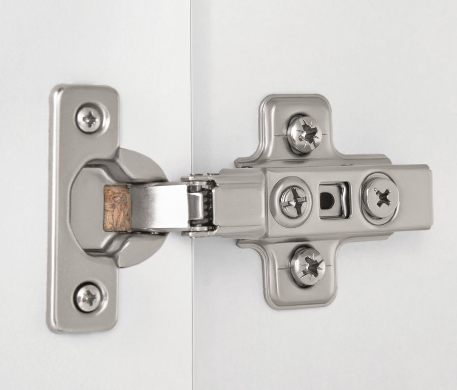 Detail stříbrného pantu na bílé vysoké skříňce do koupelny.