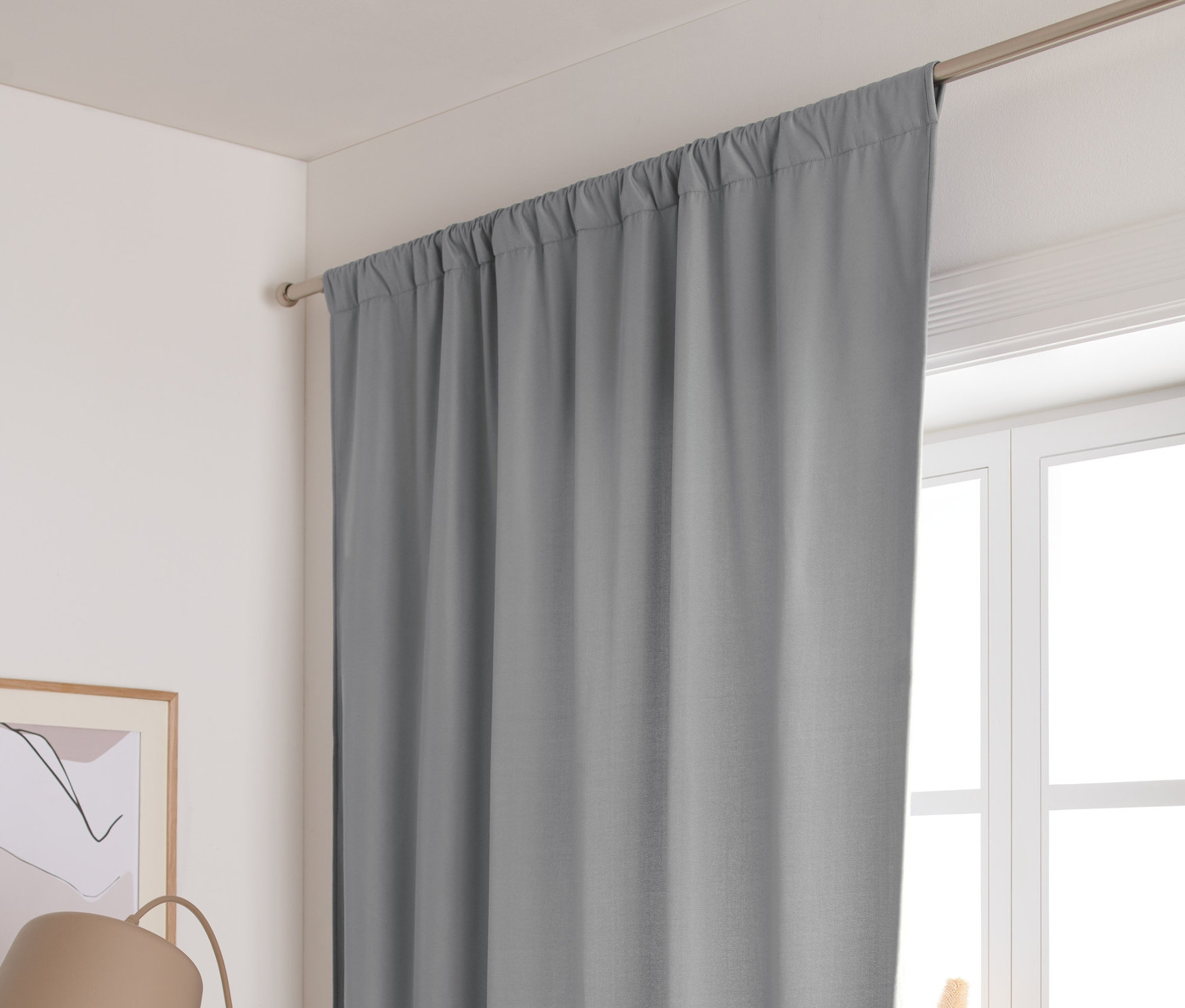 Šedý termozávěs visí na okně.