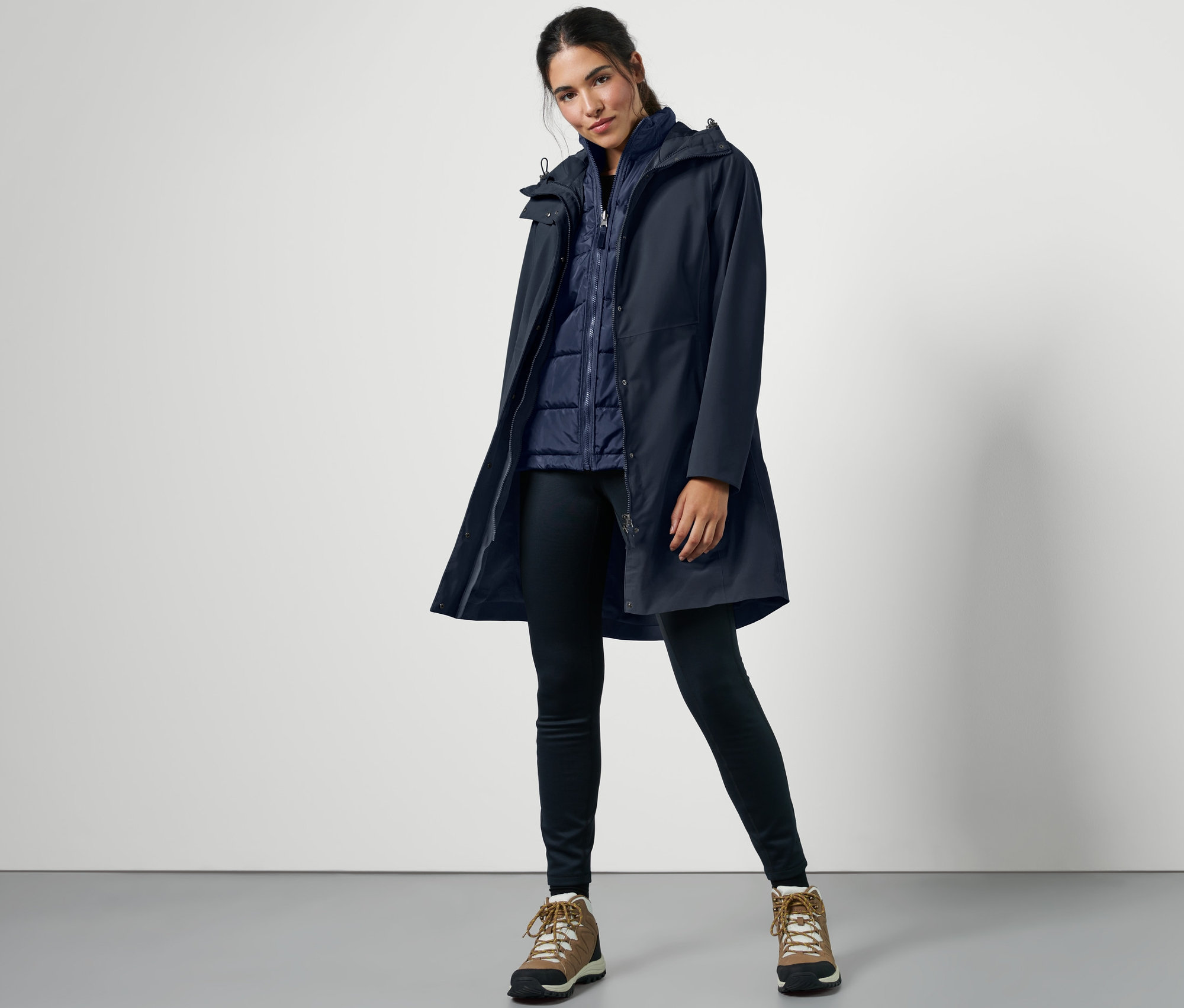 Žena pózuje v modrém outdoorovém kabátu 3 v 1 s vestou.