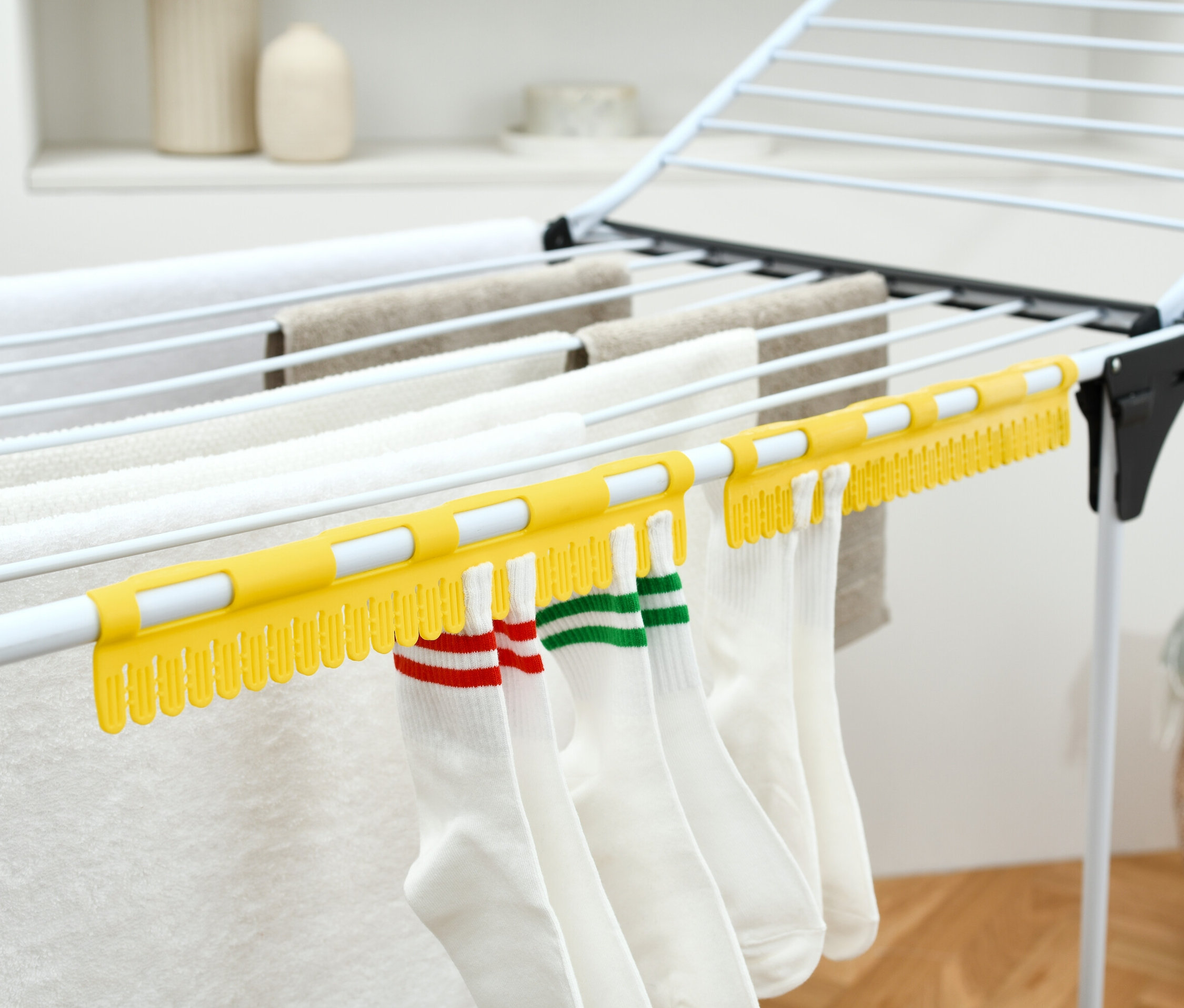 Bílé ponožky visí na žlutém sušáku na ponožky, 2 ks, na sušáku prádla.