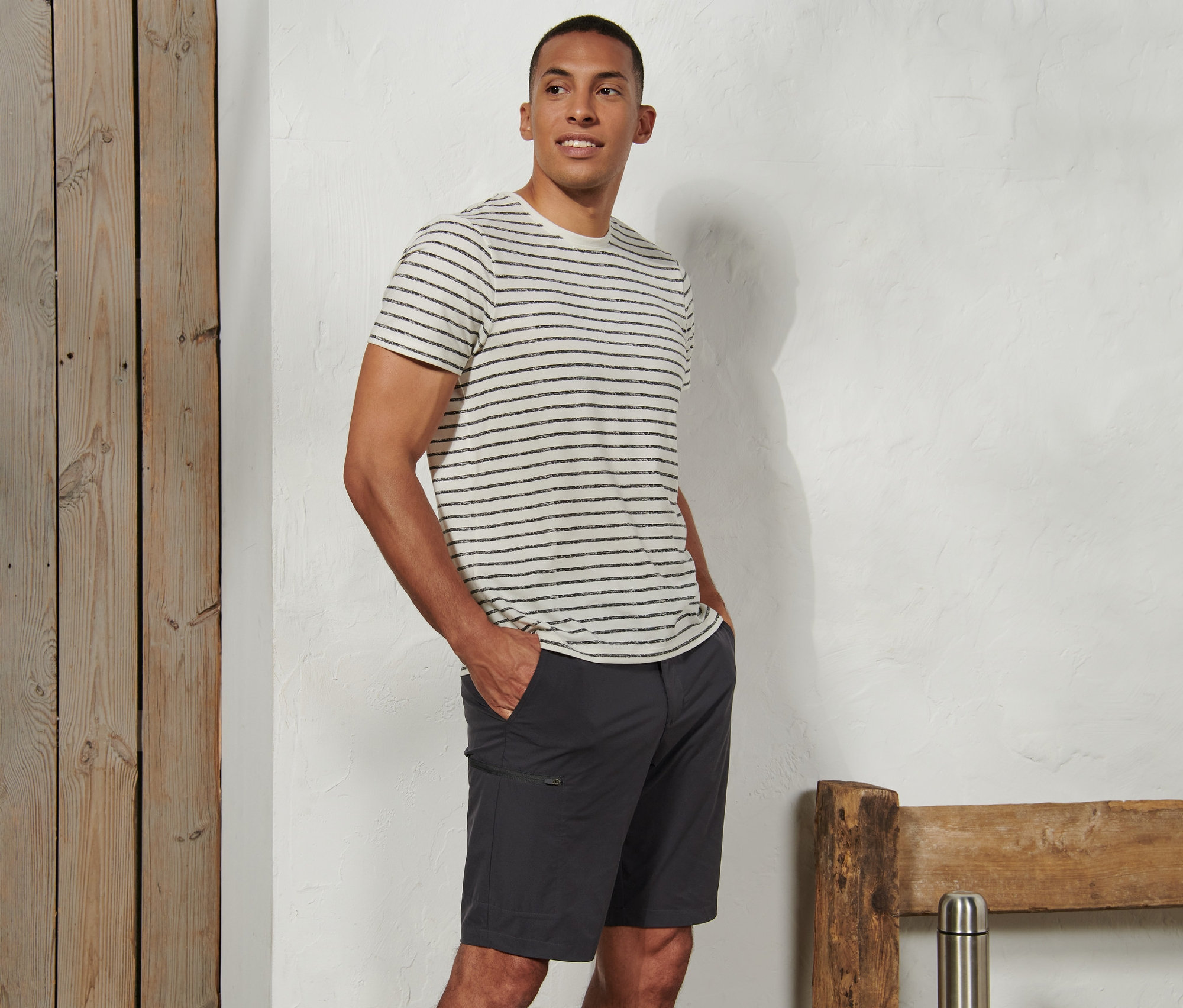 Muž stojí a má ruce v kapsách softshellových funkčních šortek.