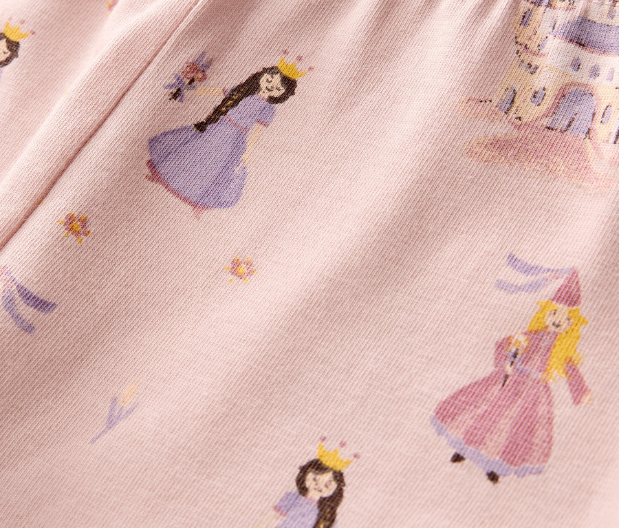 Detail růžových dětských legín s potiskem princezen a hradů.