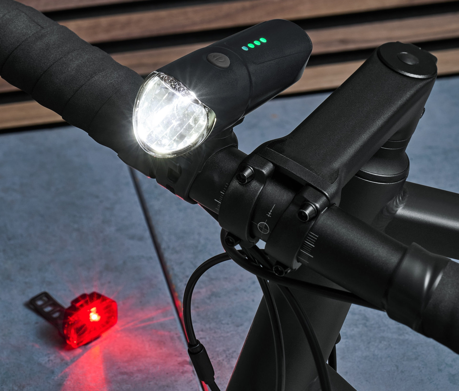 Detail černé řídítka s rozsvícenou přední a zadní svítilnou ze sady osvětlení na kolo.