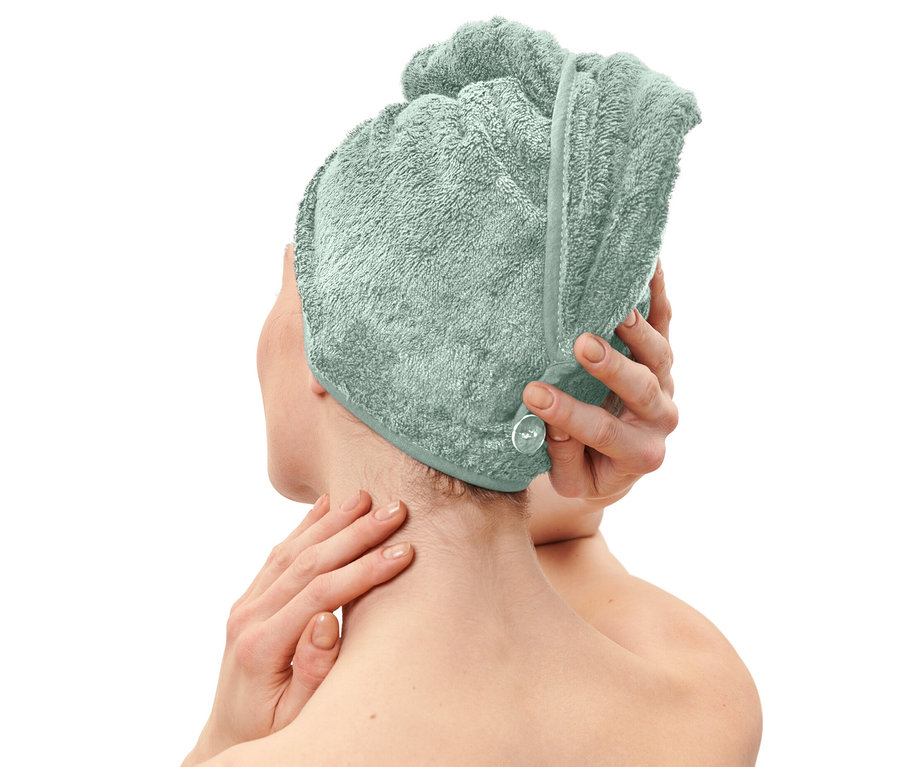 Žena si nasazuje světle modrý ručníkový turban.