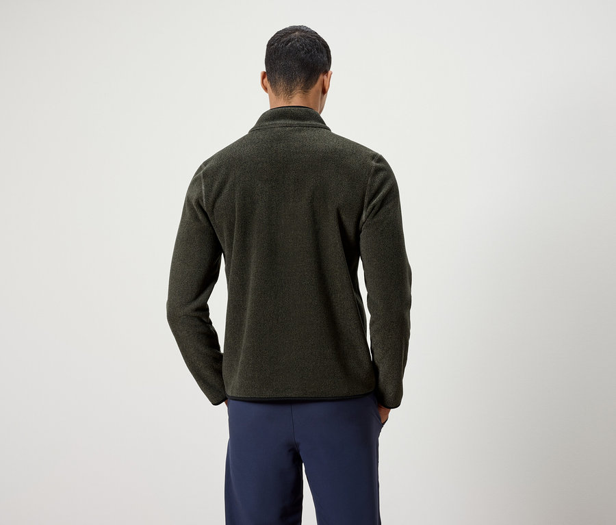 Muž zády k fotoaparátu má na sobě olivově zelenou fleecovou bundu a tmavě modré kalhoty.