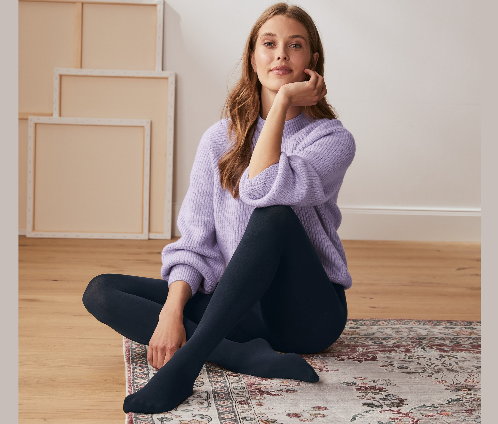 Žena sedí na podlaze na koberci a má na sobě termopunčocháče.