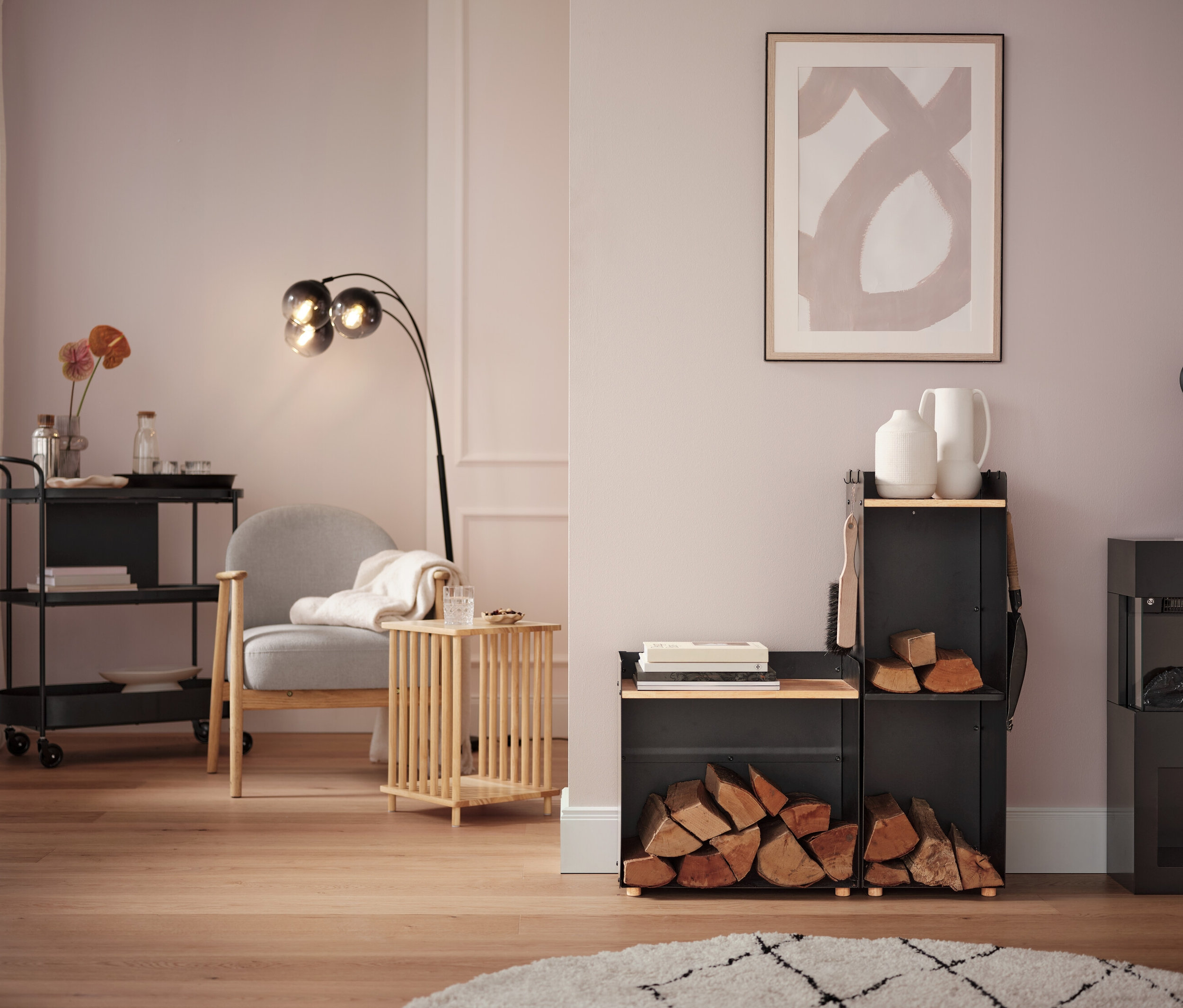 Obývací pokoj s šedým křeslem, lampou a vozíkem na kolečkách.