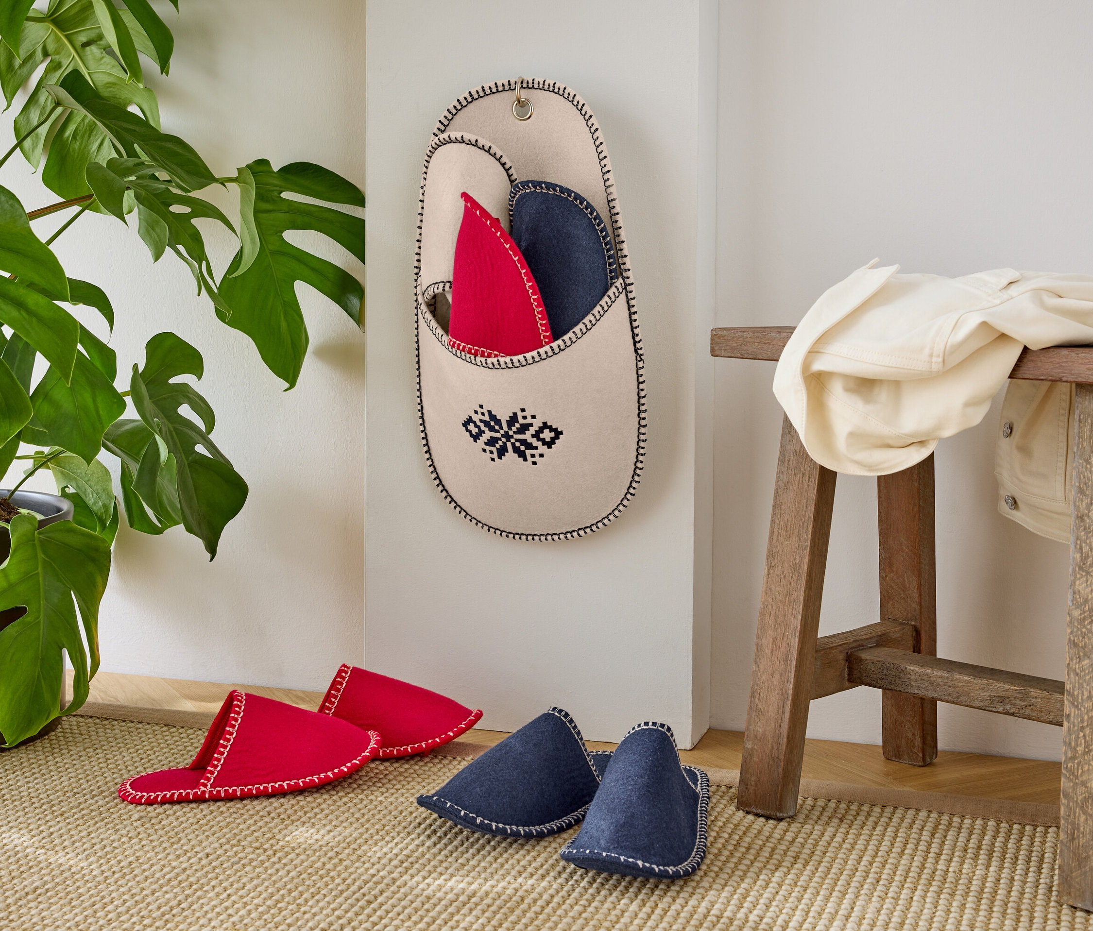 Červené a modré pantofle u zdi s rostlinou v květináči.