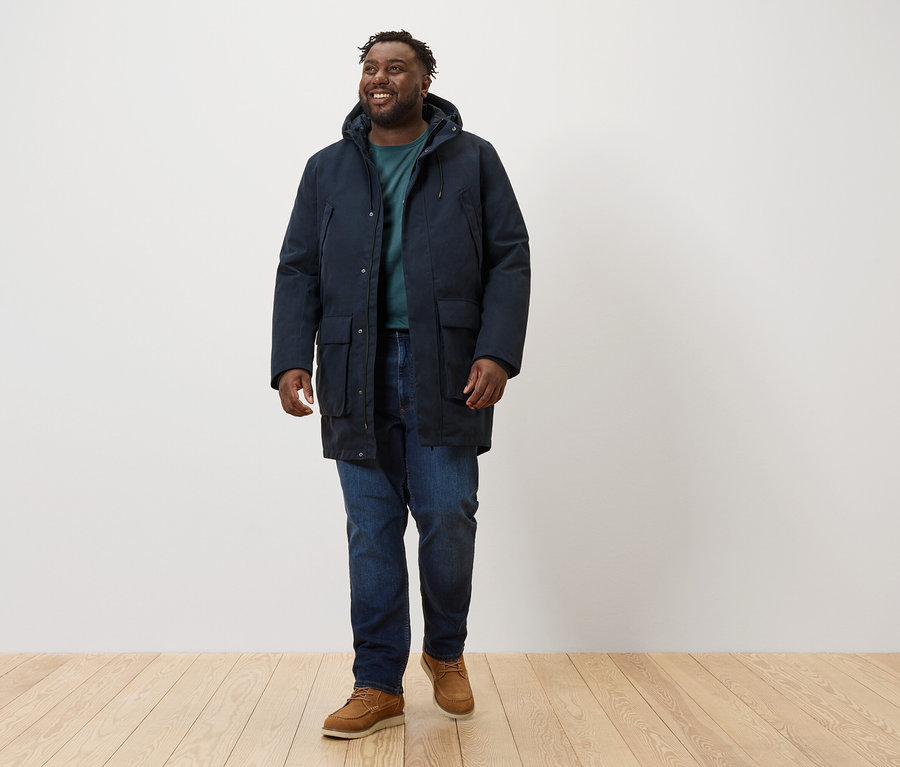 Muž kráčející a má na sobě tmavě modrou parku.