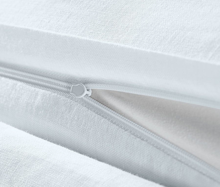 Detail bílého lněného povlečení nadměrné velikosti se zipem.