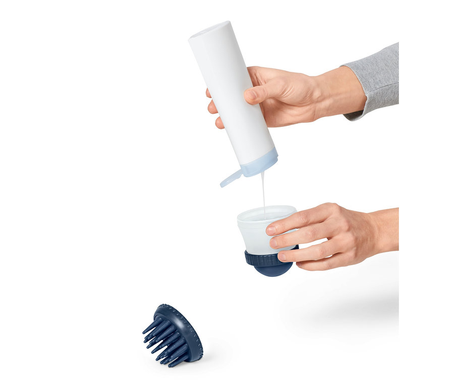 Ruka nalévá tekutinu z bílé lahve do nádoby kartáče na mytí zvířat.