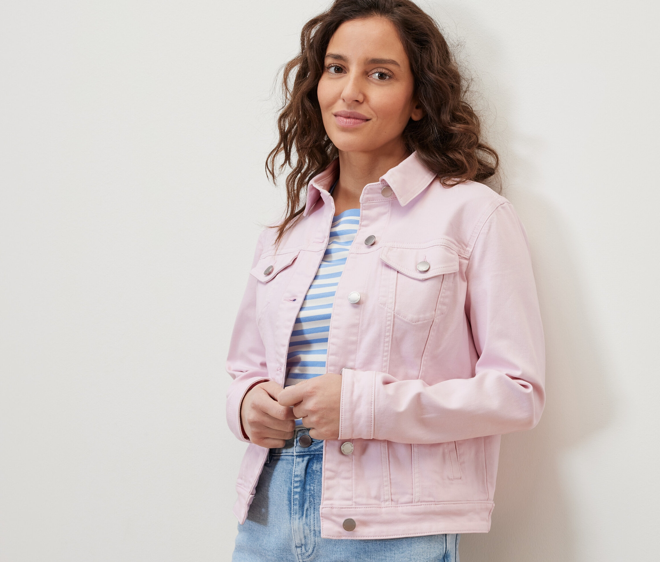 Žena má na sobě džínovou bundu a pruhované tričko.