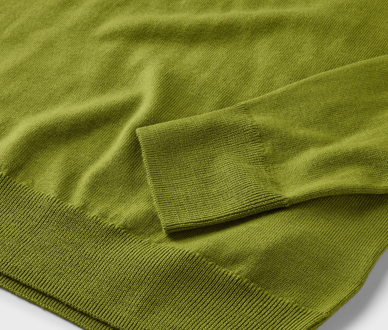 Detail světle zeleného svetru z merino vlny.