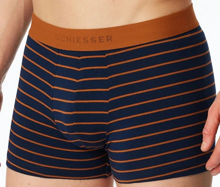 Detail osoby v tmavě modrých a oranžových proužkovaných boxerkách SCHIESSER s oranžovým pasem.