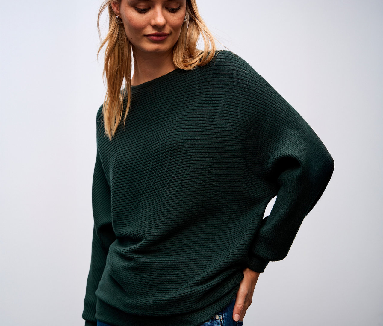 Žena má na sobě zelený strukturovaný svetr Street One a modré džíny.