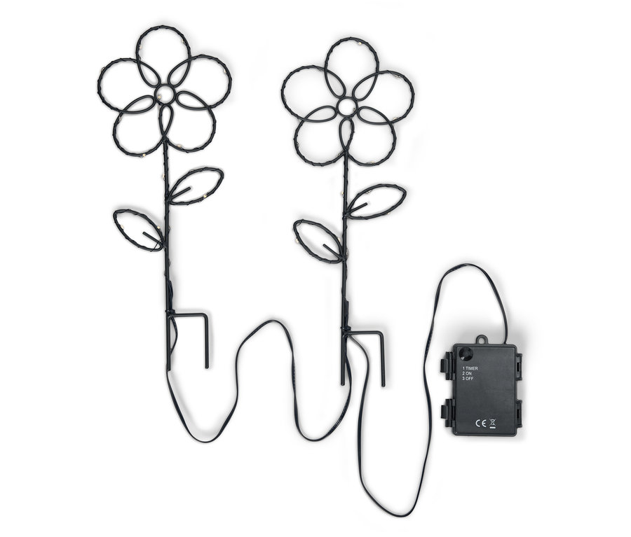 Dvě černé květinové zahradní lampy s LED světly a boxem na baterie na bílém pozadí.