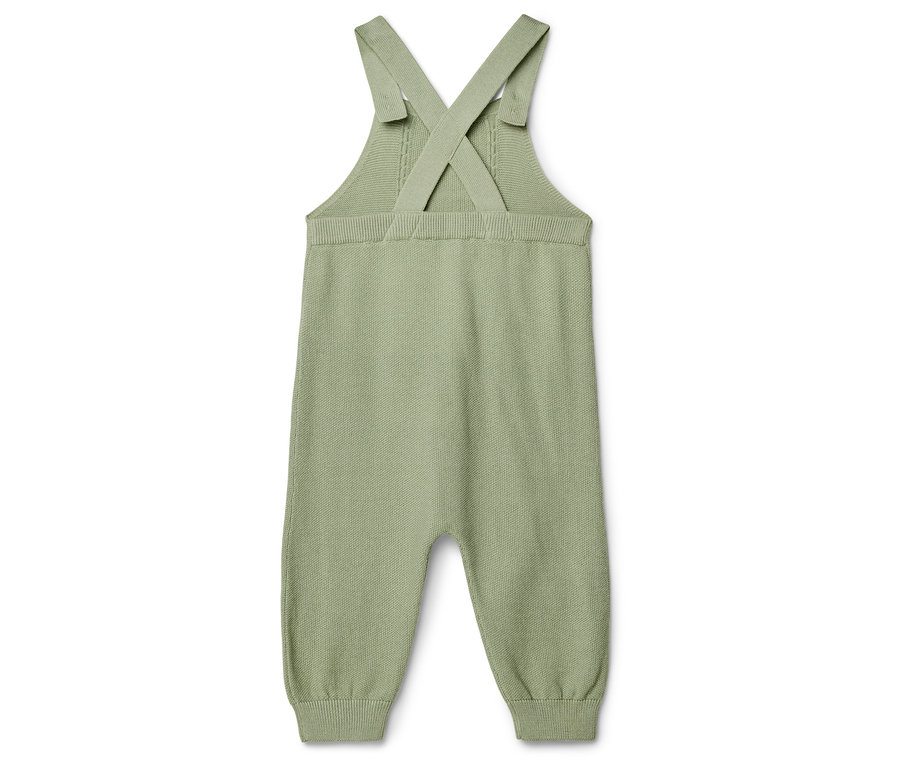 Na bílém pozadí leží jeden světle zelený pletený overal.