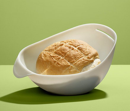 Bochník chleba v míse na pečení chleba na zeleném pozadí.