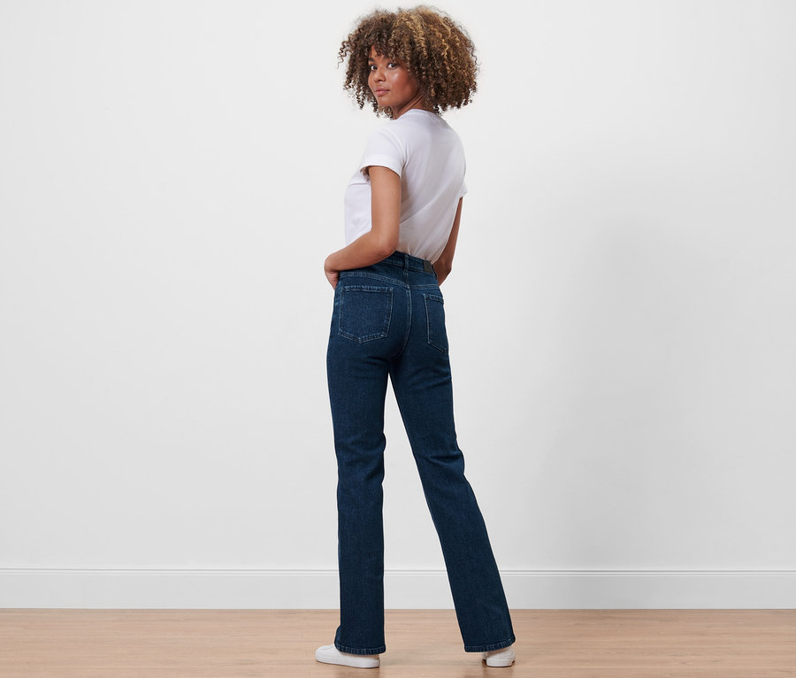Žena se dívá přes rameno a pózuje v džínách bootcut »Fit Lou« a bílém tričku.