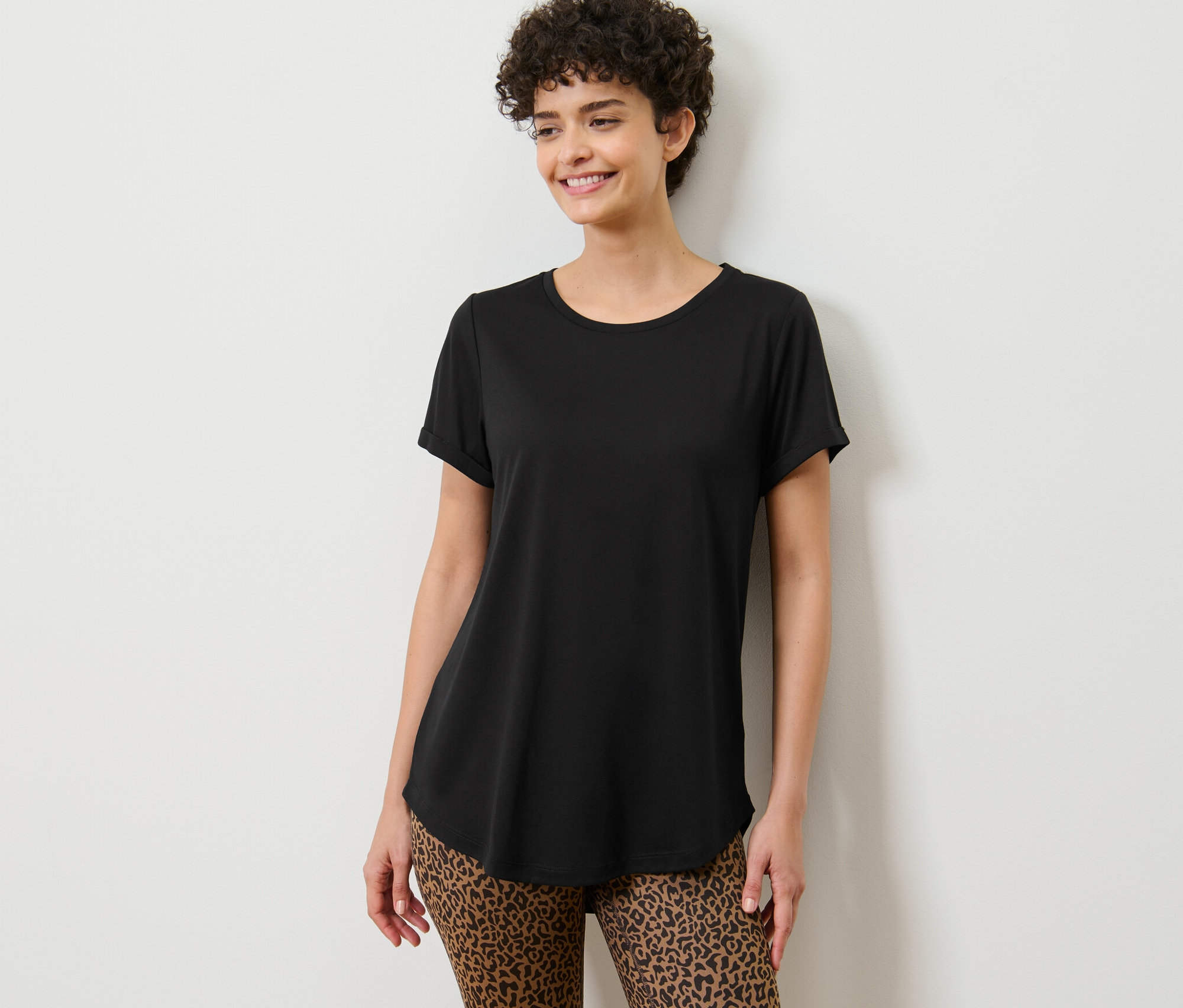 Žena pózuje v černém dlouhém tričku.