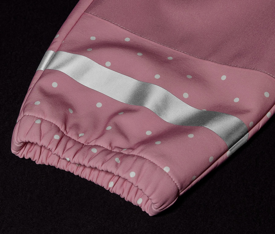 Detail dětské softshellové kombinézy s růžovým rukávem, bílými puntíky a reflexním pruhem.