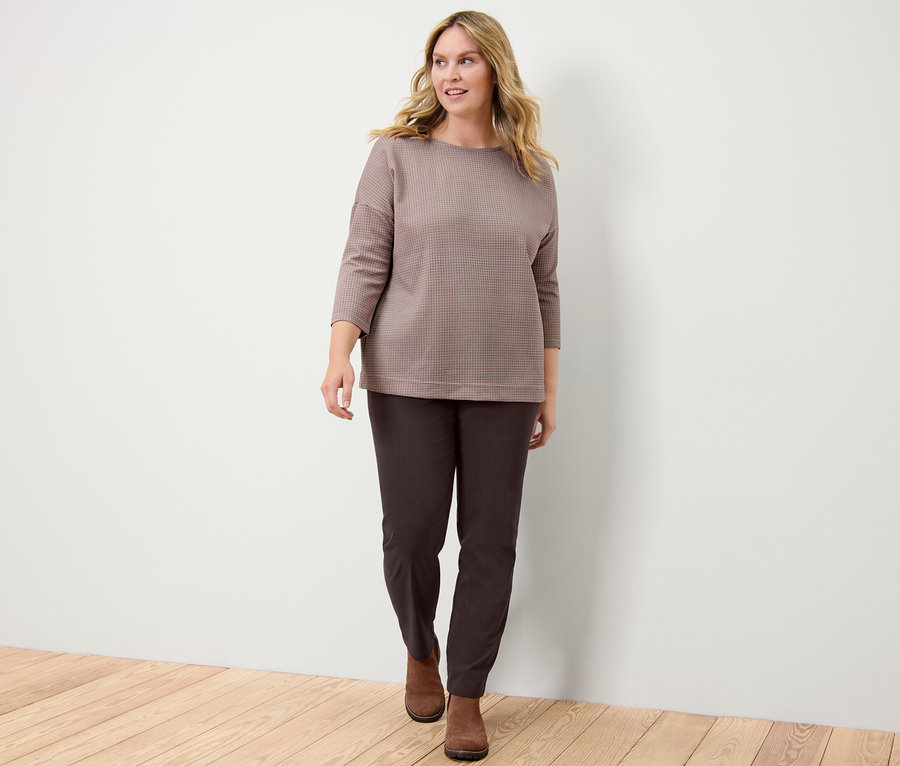 Žena v kostkované mikině a bengalínových kalhotách.