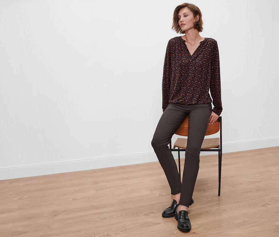 Žena sedí na židli a má na sobě halenkové triko s potiskem.