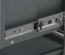 Detail šedého kovového nábytku CN3 se zásuvkou a kovovými kolejnicemi.